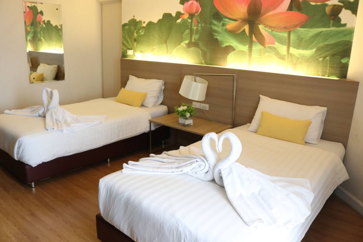 A hotel room with two beds, each with a towel arranged in a swan shape.