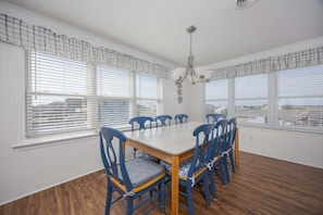 A dining room with a large table, six blue chairs, and a chandelier.