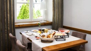 A dining area with a table set for breakfast, a window with curtains, and a view of a building outside. - Hotel am Markt (Wipperfuerth)
