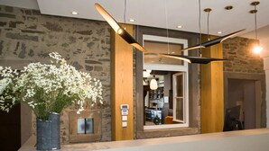 A reception area with a stone wall, a wooden door, and a modern pendant light. - Hotel am Markt (Wipperfuerth)