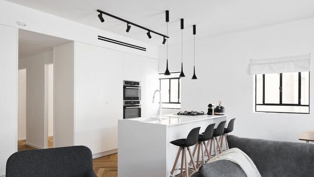 A modern kitchen with white cabinetry, a central island with bar stools, and pendant lighting. - Spacious & Modern 3BD Apartment 2-min From Beach (Tel Aviv)