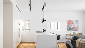 A modern kitchen with a central island, pendant lights, and a dining area with a table and chairs. - Spacious & Modern 3BD Apartment 2-min From Beach (Tel Aviv)
