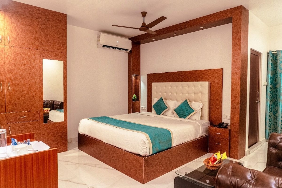 A hotel room with a large bed, a desk with a mirror, a ceiling fan, and a bathroom with a shower curtain.