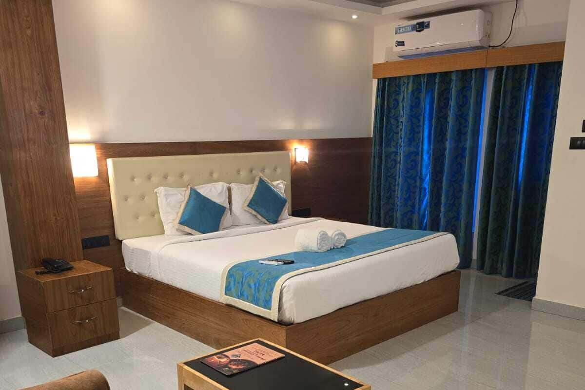 A hotel room with a large bed, a bedside table, a chair, and a ceiling fan.