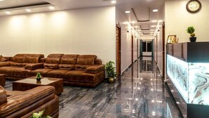 A modern lobby with leather sofas, a reception desk, and a chandelier. - Hotel De Pebbles (Port Blair)