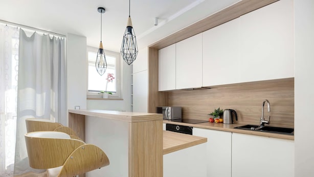 Una cocina moderna con una isla de madera, armarios blancos y un lavavajillas empotrado.