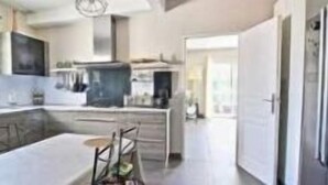 A modern kitchen with a central island, built-in appliances, and a large window providing natural light.
