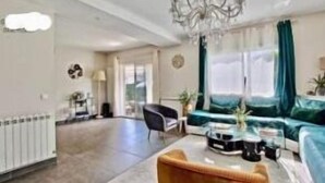 A spacious living room with a modern sofa, a coffee table, and a chandelier.