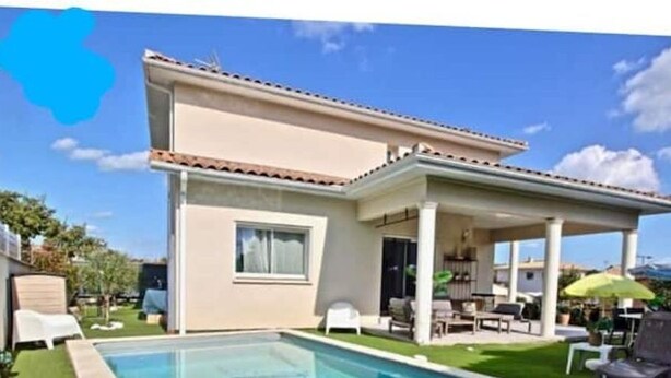 A two-story house with a covered patio, a swimming pool, and outdoor furniture.