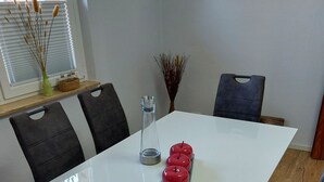 A white table with three red apples, a clear glass bottle, and a decorative vase with dried plants. - Ferienwohnung, Zimmer, Lindhorst, Steinhuder Meer (Lindhorst)