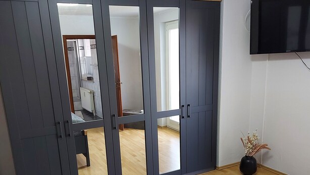 A bedroom with a bed, a wardrobe, a TV, and a view into another room. - Ferienwohnung, Zimmer, Lindhorst, Steinhuder Meer (Lindhorst)