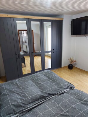 A bedroom with a bed, a wardrobe, a TV, and a view into another room. - Ferienwohnung, Zimmer, Lindhorst, Steinhuder Meer (Lindhorst)
