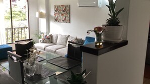 Un salon moderne avec une table basse en verre, un canapé, une table à manger et une plante en pot.