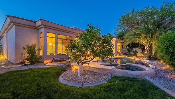 Una casa moderna con piscina, césped cuidado y mobiliario de exterior.