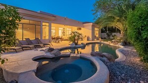 Una casa moderna con piscina, mobiliario de exterior y un jardín bien cuidado.