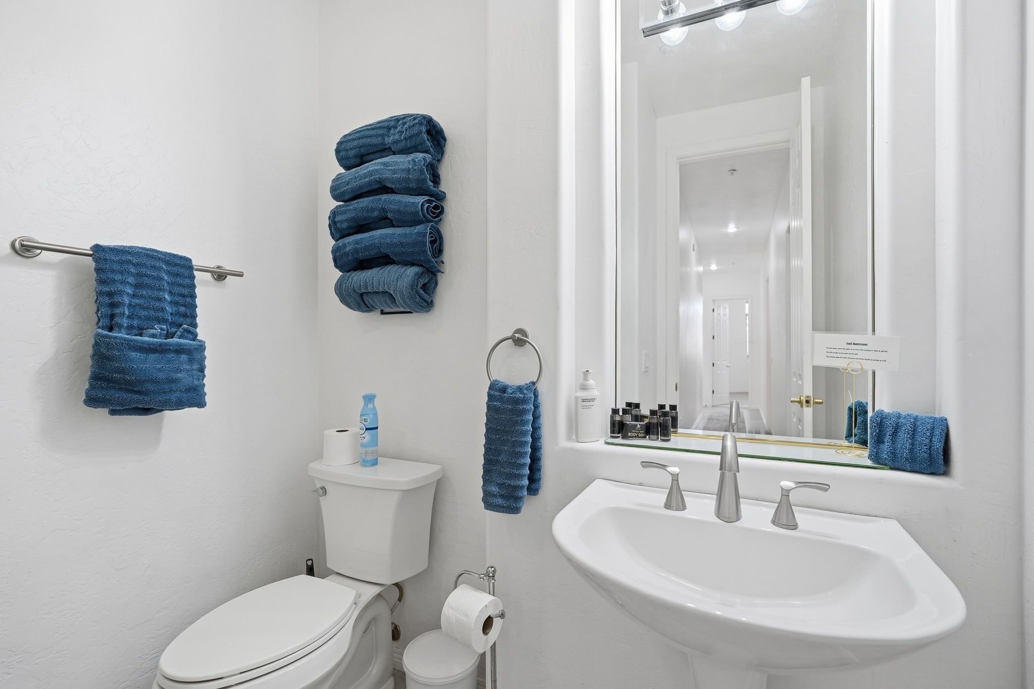 Et badeværelse med toilet, håndvask og håndklæder.