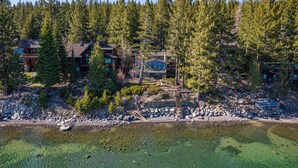 A lodge surrounded by dense forest, with a clear view of the surrounding landscape and a rocky shoreline. - Sapphire Lakefront in Dollar Point, 3BR + 1BR Guest Unit, with Buoy! (Tahoe City)