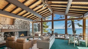A cozy living room with a stone fireplace, comfortable seating, and a view of the lake. - Sapphire Lakefront in Dollar Point, 3BR + 1BR Guest Unit, with Buoy! (Tahoe City)