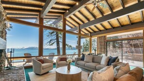 A spacious living area with a large window overlooking a lake, furnished with sofas, chairs, and a coffee table. - Sapphire Lakefront in Dollar Point, 3BR + 1BR Guest Unit, with Buoy! (Tahoe City)