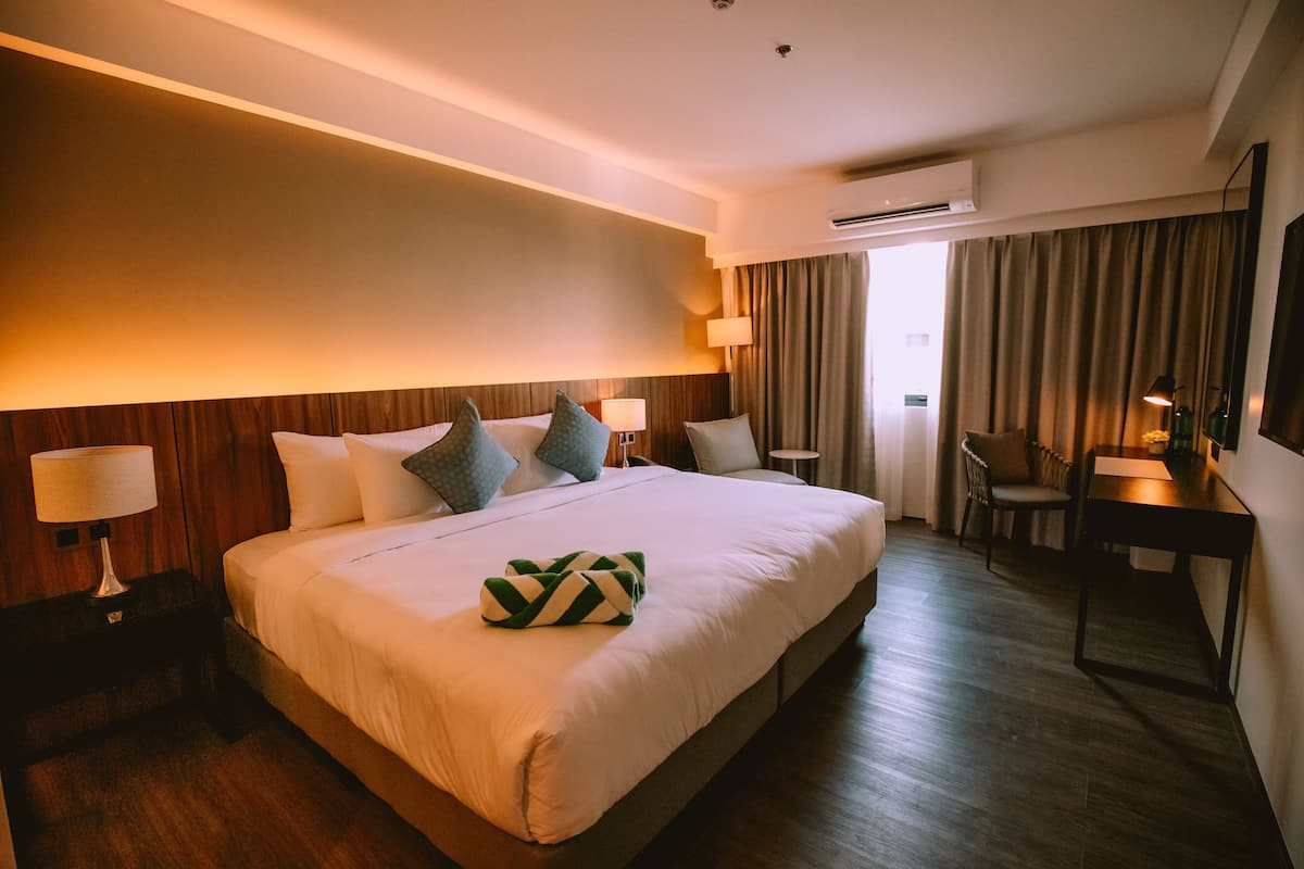 Una habitación de hotel con una cama grande, mesitas de noche con lámparas, un escritorio y una silla.