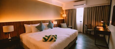 Une chambre d’hôtel avec un grand lit, des tables de chevet avec des lampes, un bureau et une chaise.