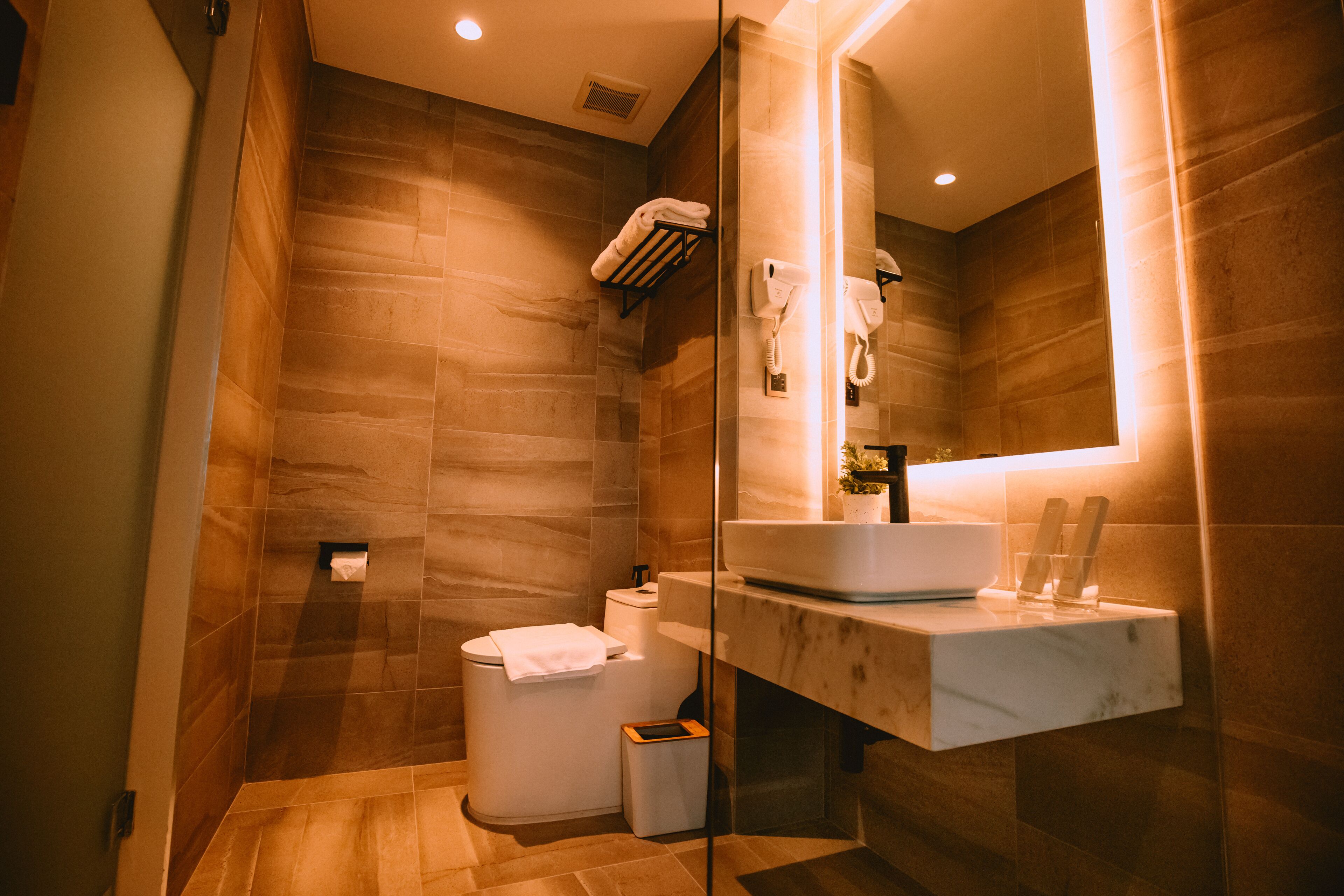 Un baño moderno con lavamanos de mármol, cabina de ducha de vidrio y un perchero para toallas.