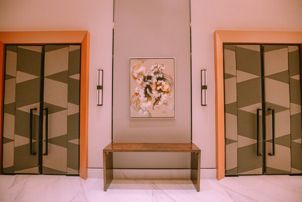 A room with a bed, a bench, and two doors with geometric patterns. - The Maximilian Hotel (Cauayan)