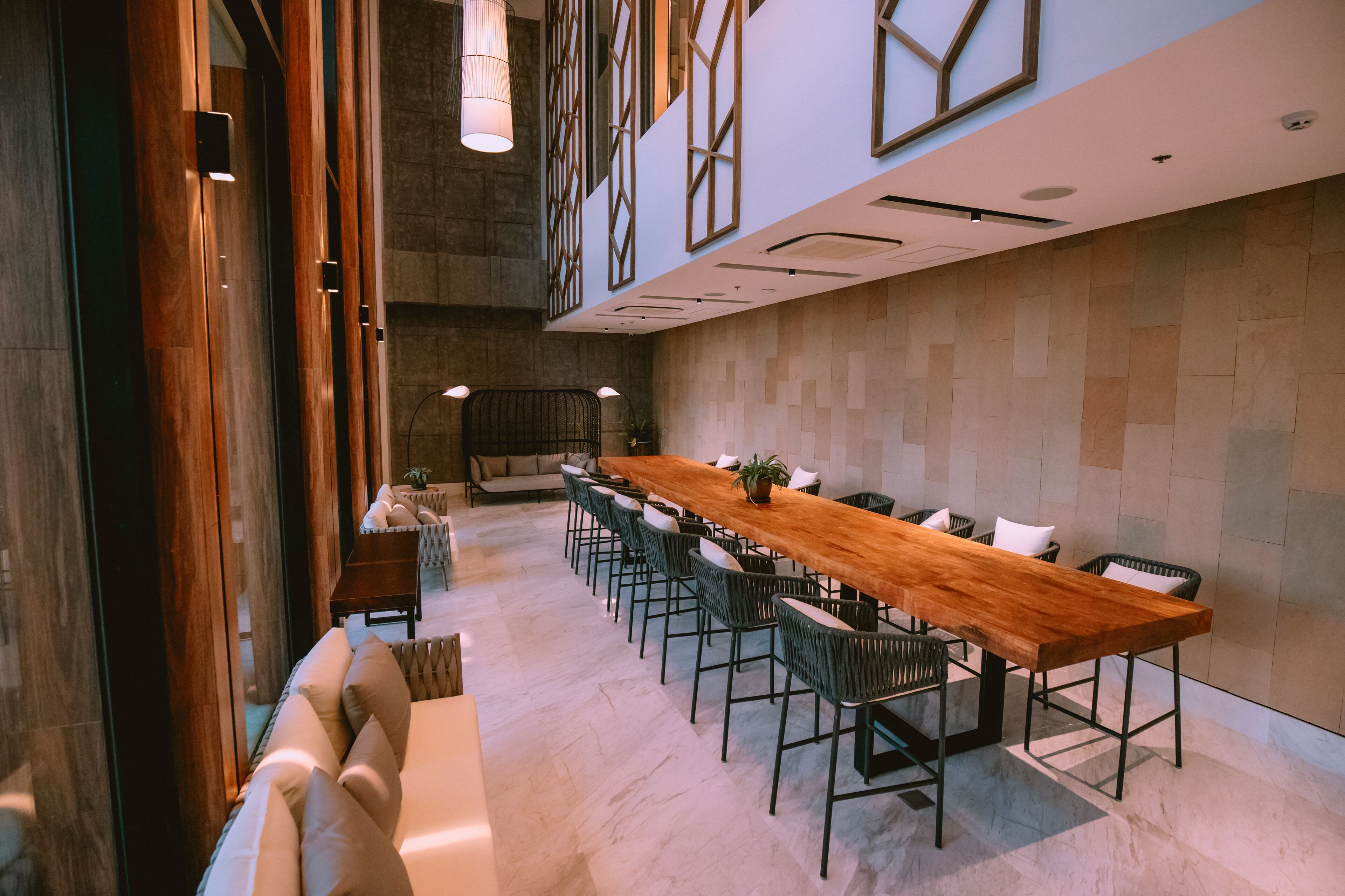Une salle de conférence avec une longue table en bois, des chaises noires et un canapé.