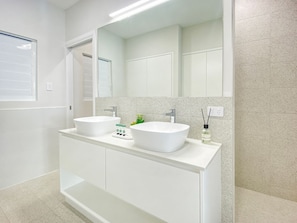 Une salle de bain avec deux lavabos blancs, un grand miroir et un meuble-lavabo blanc.
