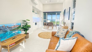 A modern living room with a flat-screen TV, leather sofa, and a dining area with a table and chairs.