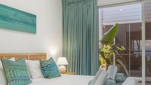 Une chambre d’hôtel moderne avec un grand lit, une fenêtre avec des rideaux, un ventilateur de plafond et une vue sur l’extérieur.