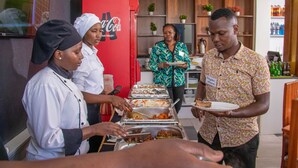 Un buffet avec plusieurs plateaux de nourriture et un réfrigérateur rempli de Coca-Cola.