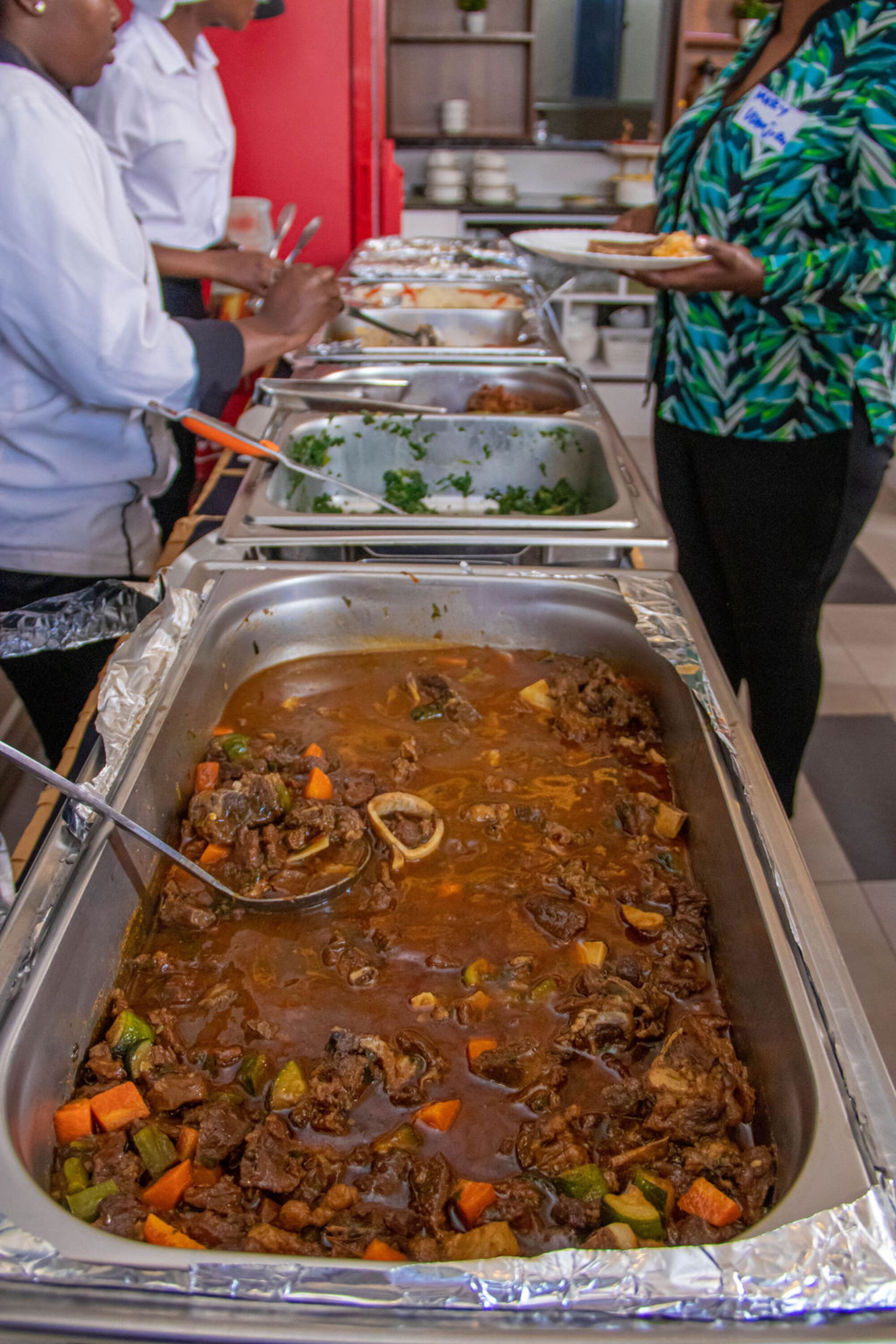 A buffet with a variety of dishes including a large pot of stew with vegetables.