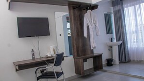 Une salle de bain moderne avec un meuble-lavabo en bois, un évier, un miroir et un peignoir suspendu à un porte-serviettes.