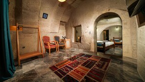 A rustic room with a wooden ladder, two chairs, a patterned rug, and a bed with a headboard. - Caverna Hotel Premium Caves (Nevsehir)