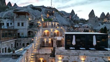 A hotel with a central courtyard, stone buildings, and a view of volcanic mountains.