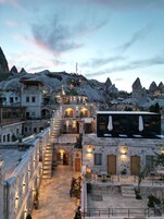 A hotel with a central courtyard, stone buildings, and a view of volcanic mountains.