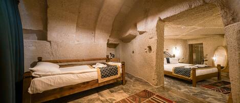 A rustic room with two wooden beds, a stone ceiling, and a large mirror.