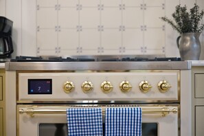 A kitchen with a digital clock, a stove with six burners, and a checkered towel hanging on a rod. - Pro Designer Cottage, 4/10 Mile to New Circle Beach (Lakeside)