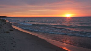 A beach at sunset with waves and a clear sky. - Pro Designer Cottage, 4/10 Mile to New Circle Beach (Lakeside)