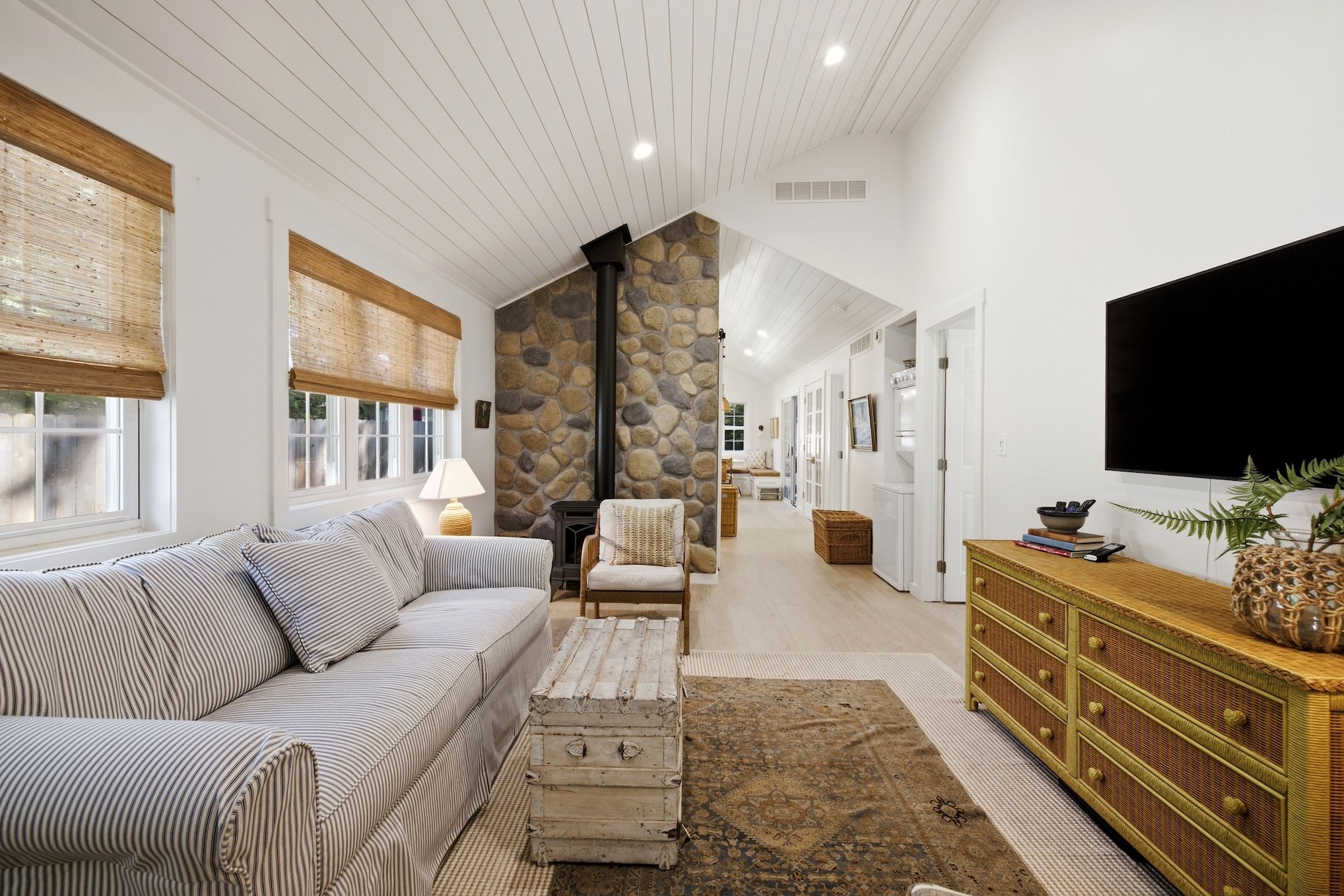 A spacious living room with a sofa, armchair, and a television.