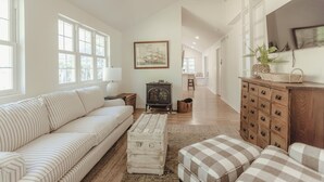 A spacious living room with a striped sofa, a vintage radio, and a wooden cabinet. - Pro Designer Cottage, 4/10 Mile to New Circle Beach (Lakeside)