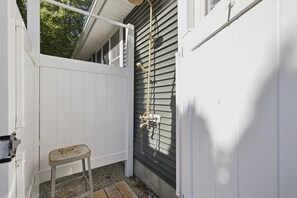A small outdoor area with a white fence, a metal bench, and a hose attached to a wall. - Pro Designer Cottage, 4/10 Mile to New Circle Beach (Lakeside)