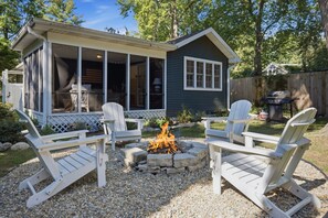 A covered outdoor seating area with Adirondack chairs and a fire pit.