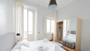 Ein Hotelzimmer mit einem großen Bett, einem Kleiderschrank und einem Balkon.
