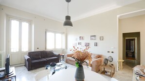Ein geräumiges Wohnzimmer mit einem großen weißen Tisch, zwei Sofas und einem Blumenstrauß.