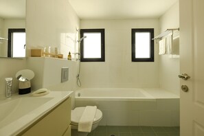 A bathroom with a bathtub, toilet, and a window. - Beachside 3-BR Apt Perfect for Families (Tel Aviv)
