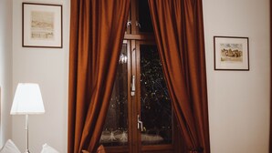A hotel room with a bed, white bedding, a lamp, brown curtains, and framed pictures on the walls. - Villa Eckhoff (Stavanger)