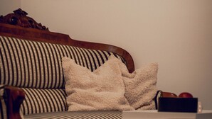 A striped sofa with a wooden frame, a white throw blanket, and a small black box on the floor. - Villa Eckhoff (Stavanger)