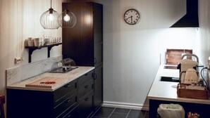 A modern kitchen with dark cabinetry, a marble countertop, and pendant lighting. - Villa Eckhoff (Stavanger)